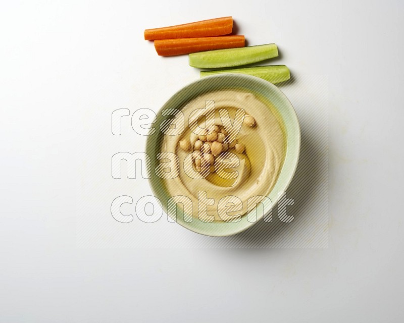 Hummus in a green plate garnished with roasted chickpeas  on a white background