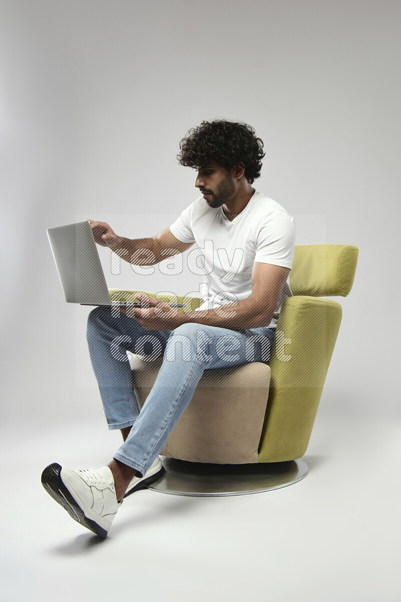 A man wearing casual sitting on a chair working on a laptop on white background