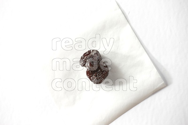 Two dried plums on a piece of paper on a white background in different angles