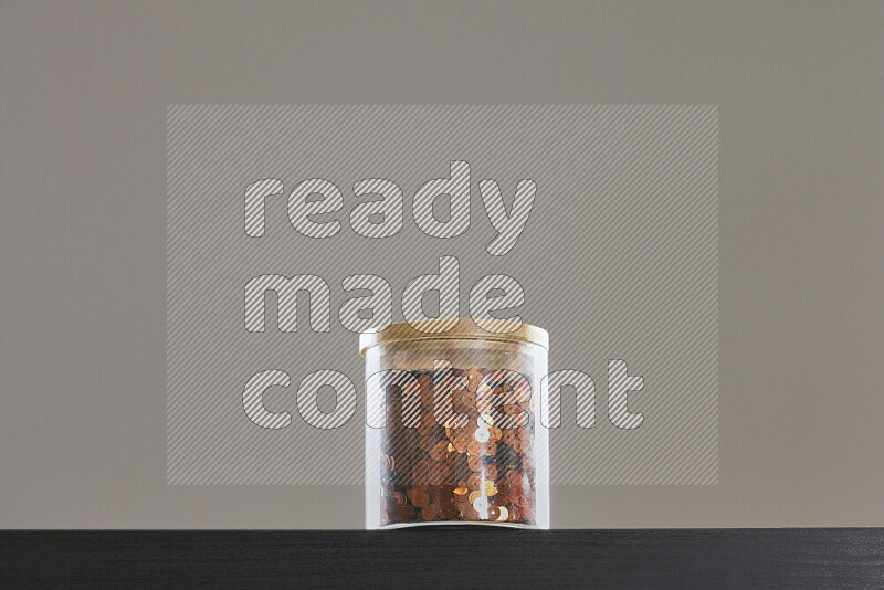 Sequins in a glass jar on black background