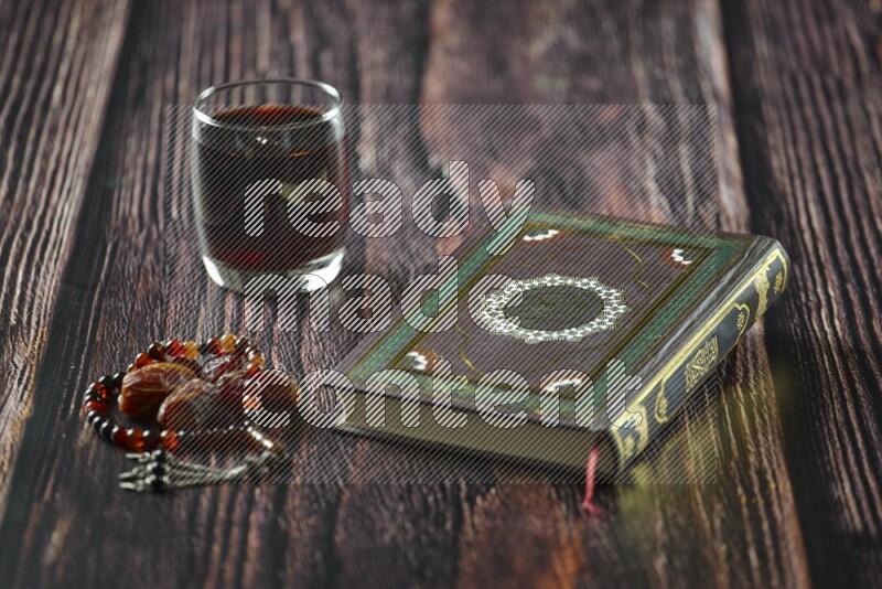 Quran with dates, prayer beads and different drinks all placed on wooden background