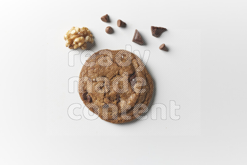 A single chocolate chips cookie with chocolate and walnuts beside it on a white background