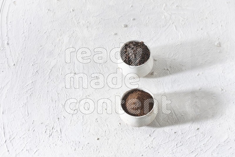 وعاءين من السيراميك بيج اللون، أحدهما مملوء بالقرنفل والآخر مملوء بالبودرة على أرضية بيضاء