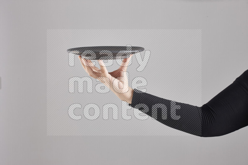 A woman in black abaya holding different pottery essentials in different positions