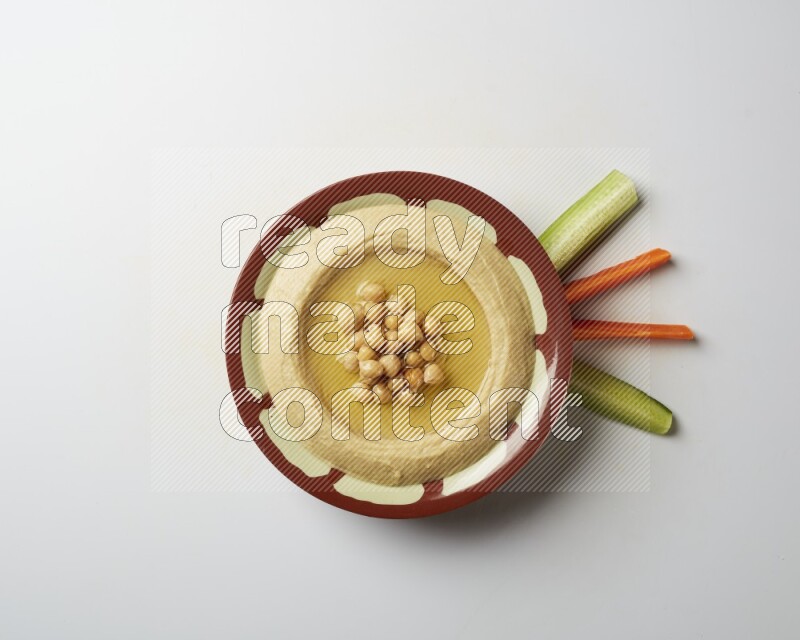 Hummus in a traditional plate garnished with roasted chickpeas  on a white background