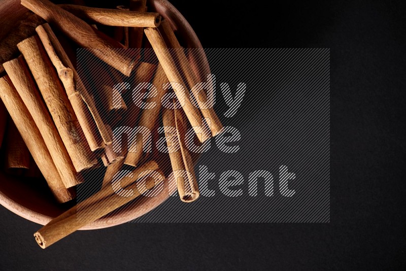 Cinnamon Sticks in a wooden bowl on black background