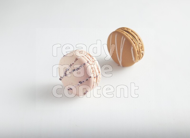 45º Shot of of two assorted Brown Irish Cream, and pink orange blossom macarons on white background