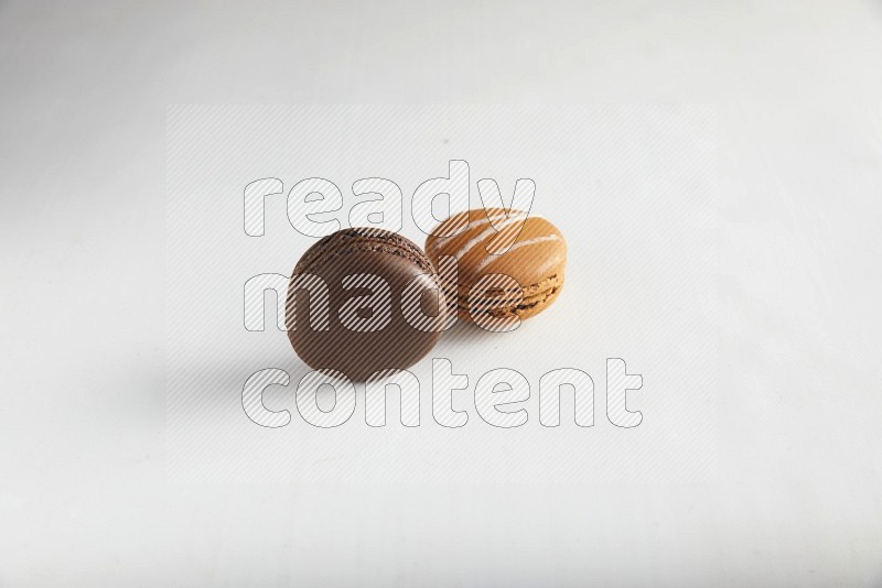 45º Shot of of two assorted Brown Irish Cream, and Brown Dark Chocolate macarons on white background