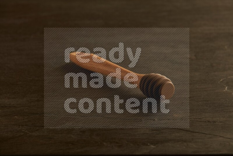 Wooden honey dipper on black slate background