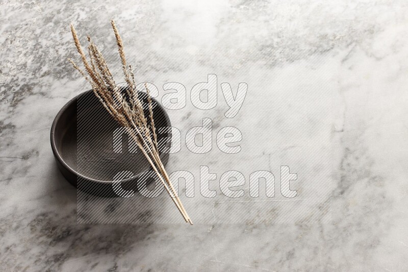 Wheat stalks on Black Pottery Oven Plate on grey marble flooring, 45 degree angel