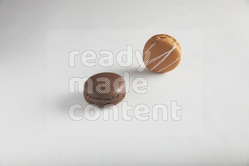 45º Shot of of two assorted Brown Irish Cream, and Brown Dark Chocolate macarons on white background
