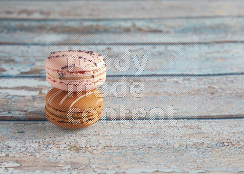 45º Shot of of two assorted Brown Irish Cream, and pink orange blossom  macarons on light blue background