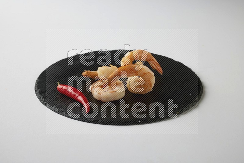 four grilled shrimp  on a black slate direct  on a white back ground