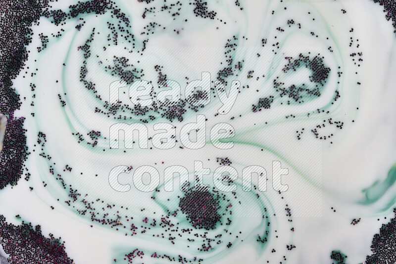 A close-up of sparkling purple glitter scattered on swirling green and white background
