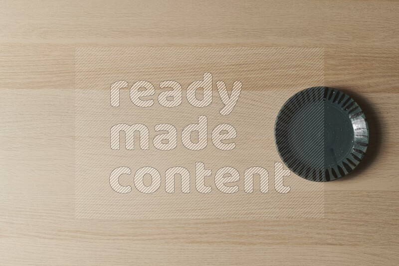 A dark green pottery plate on light wooden background