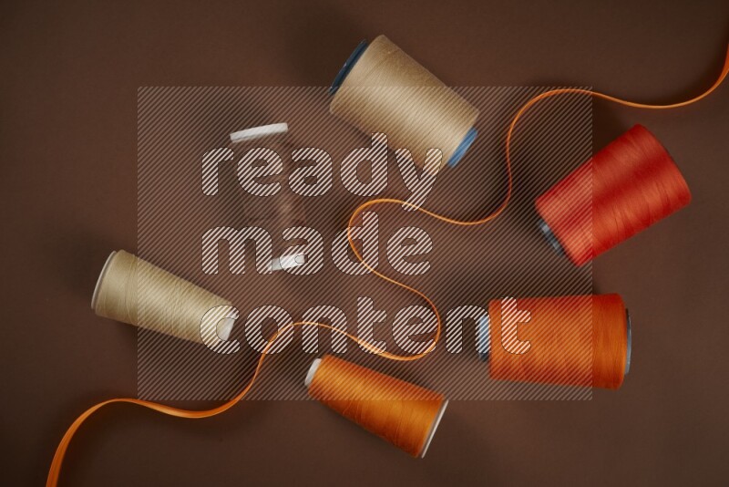 An orange collection of sewing and tailoring tools arranged on a brown background