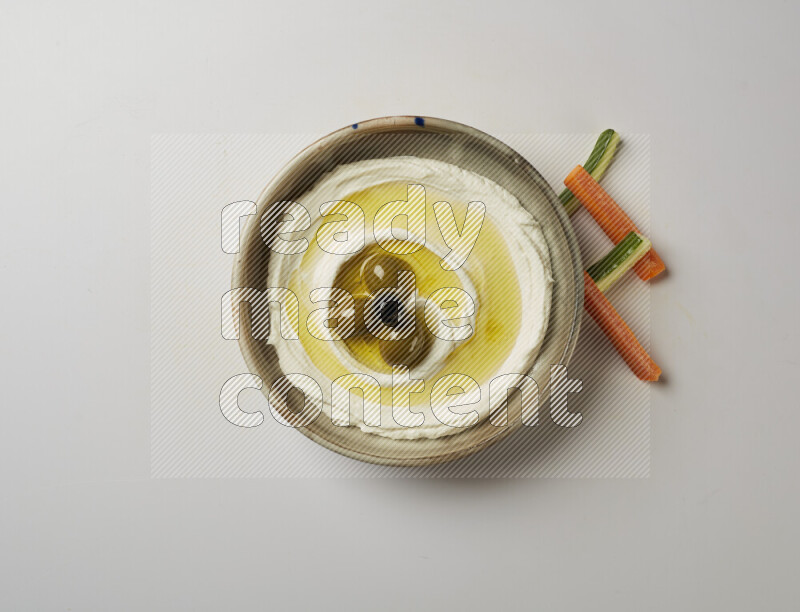 Lebnah garnished with whole olives in a grey pottery plate on a white background