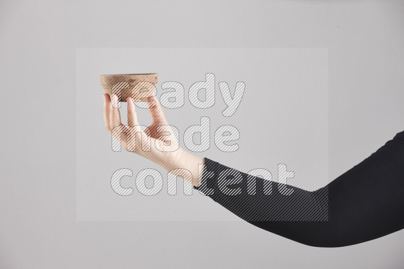 A woman in black abaya holding different wooden essentials in different positions
