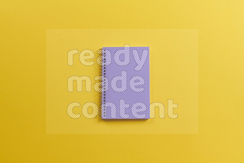 A purple notebook with different school supplies on yellow background