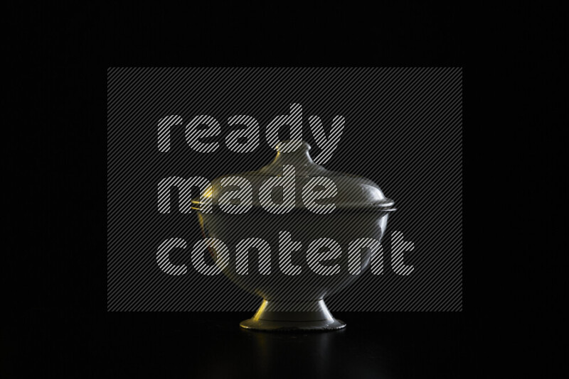 A vintage metal pot with colored rim light against black background