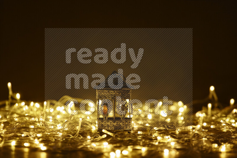 A traditional ramadan lantern surrounded by glowing fairy lights in a dark setup