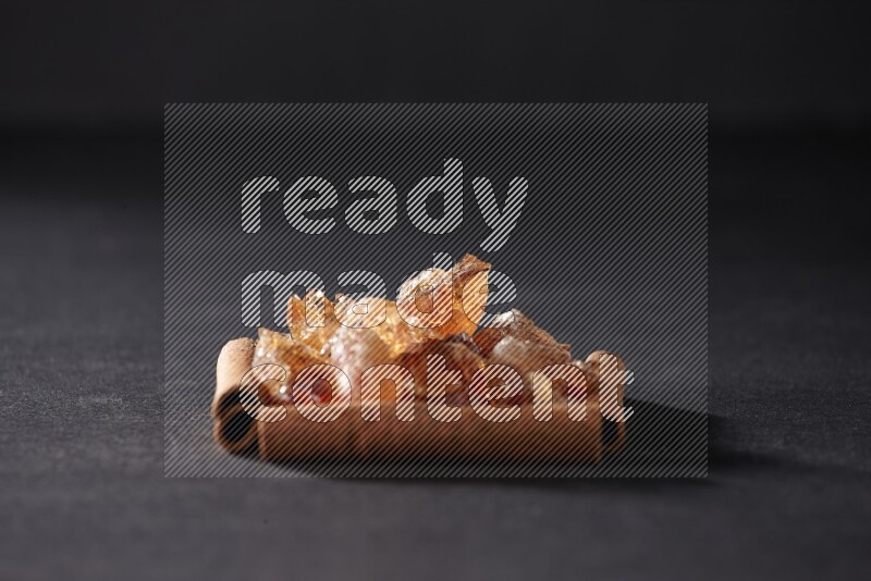 A single square of cinnamon sticks full of Arabic gum on black flooring