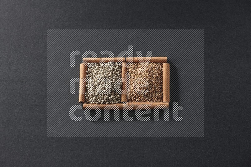 مربعان من أعواد القرفة ممتلئان بحبوب الخردل وحبوب الفلفل الأبيض علي خلفية سوداء