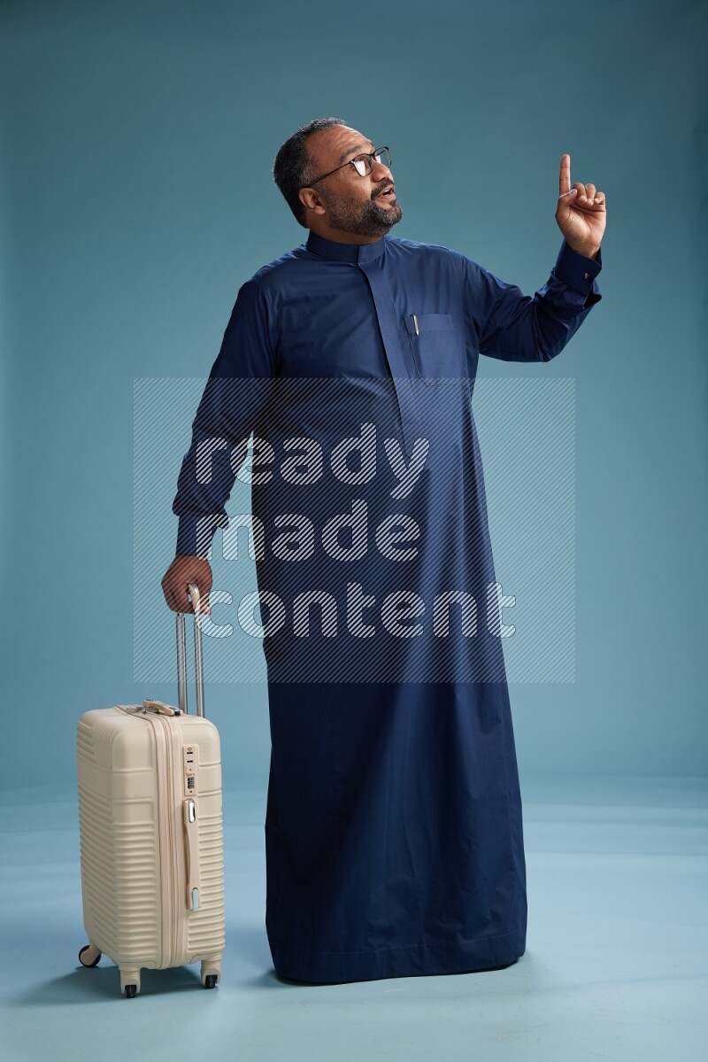 Saudi Man without shimag Standing pulling travel bag on blue background