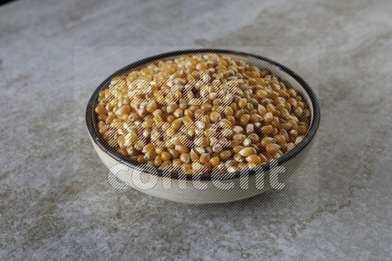 corn kernel in a multi-colored pottery bowl on a grey textured countertop