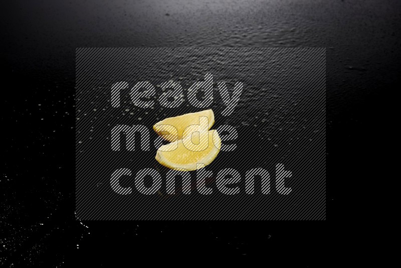 Lemon wedges with water drops, and droplets on black background