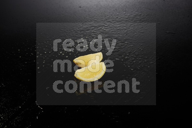 Lemon wedges with water drops, and droplets on black background