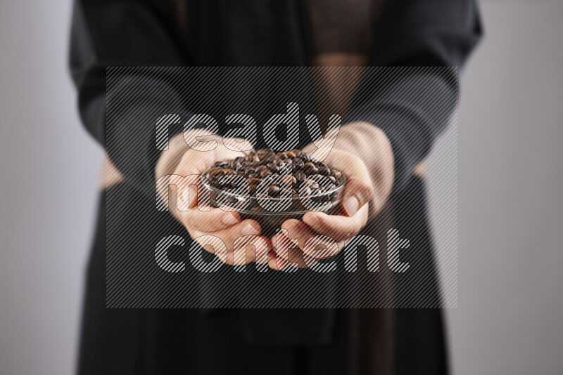 Woman in abaya holding different kinds of coffee beans in different positions