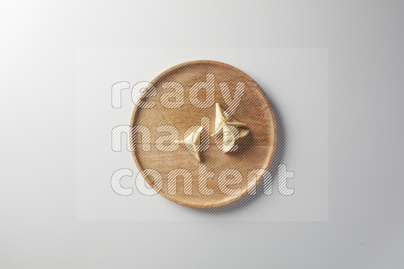 Three Sambosas on a wooden round plate on a white background