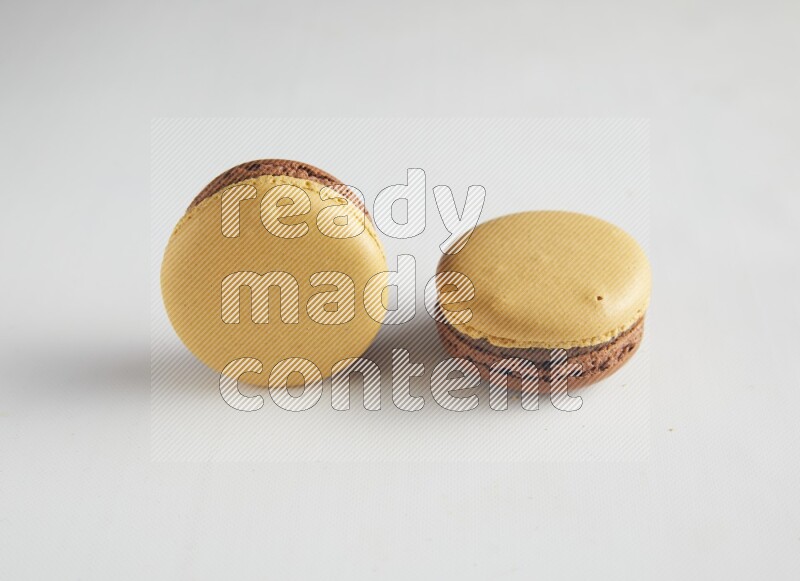 45º Shot of two Yellow and Brown Chai Latte macarons on white background