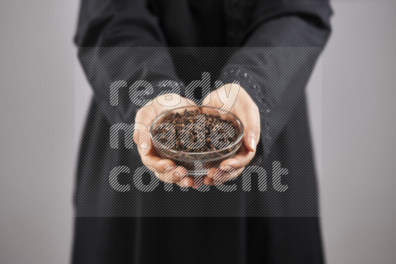 Woman in abaya holding different kinds of spices in different positions