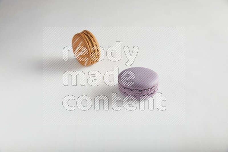 45º Shot of of two assorted Brown Irish Cream, and Purple Blueberry macarons on white background