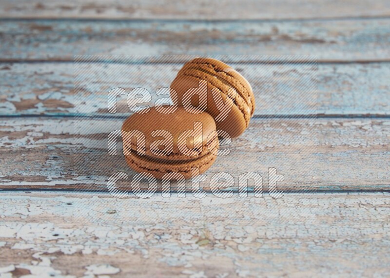 45º Shot of of two assorted Brown Irish Cream, and Brown Coffee macarons on light blue background