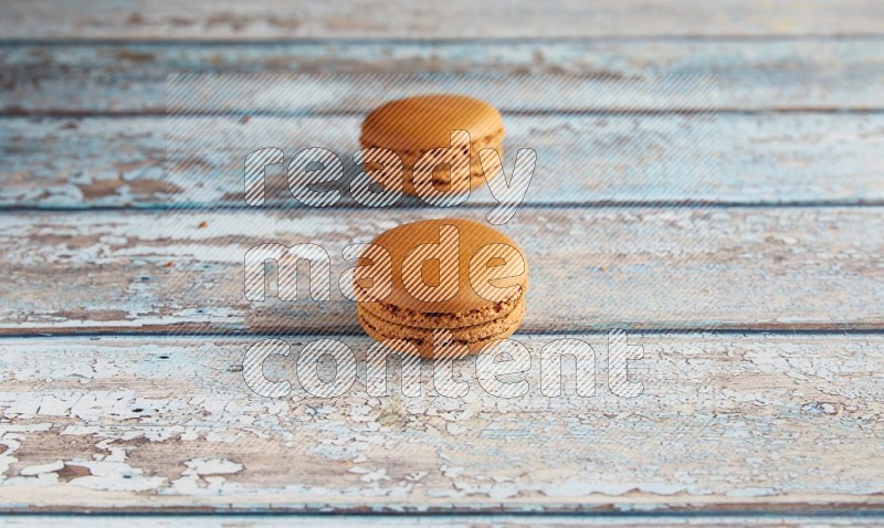 45º Shot of two Brown Maple Taffy macarons on light blue wooden background