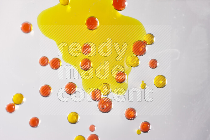 Close-ups of abstract yellow and red watercolor drops on oil Surface on white background