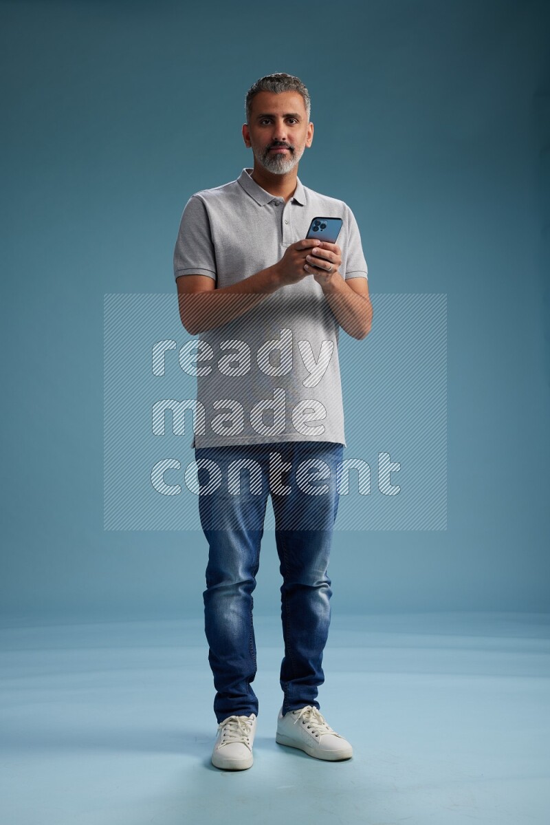Man Standing texting on phone on blue background