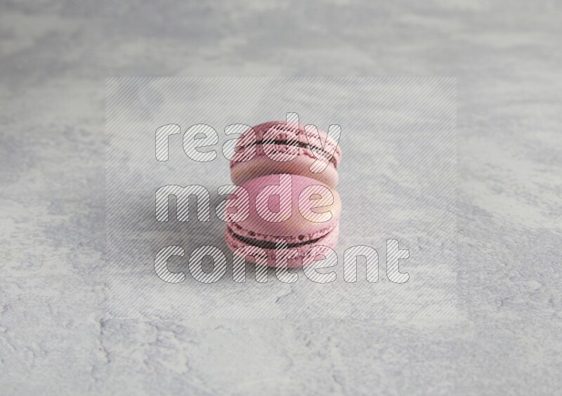 45º Shot of two Purple Strawberry macarons on white  marble background