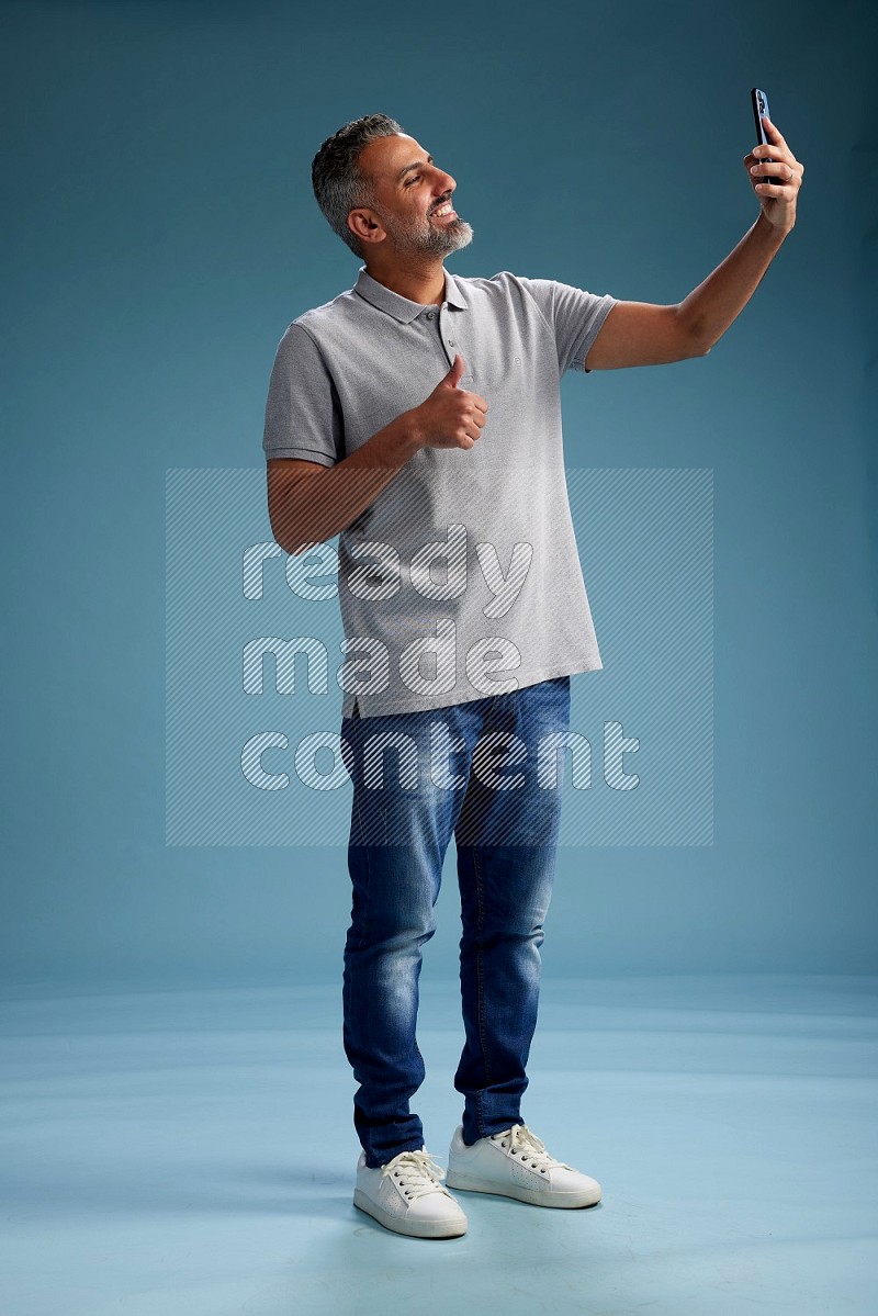 Man Standing taking selfie on blue background