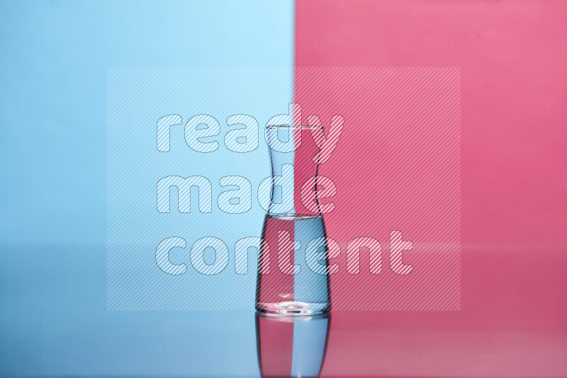 The image features a clear glassware filled with water, set against light blue and pink background