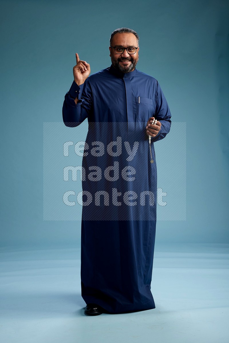 Saudi Man without shimag Standing Interacting with the camera on blue background