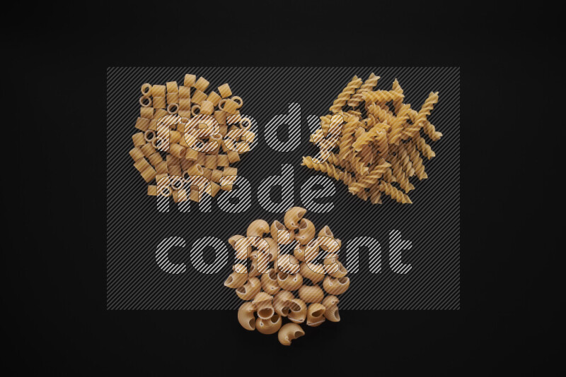Different pasta types in bunches on black background