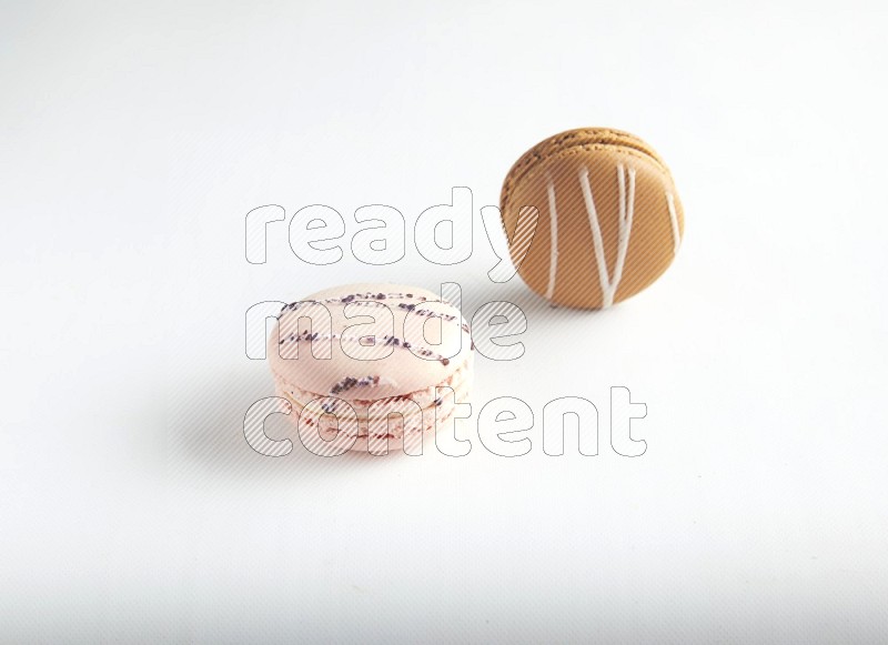 45º Shot of of two assorted Brown Irish Cream, and pink orange blossom macarons on white background