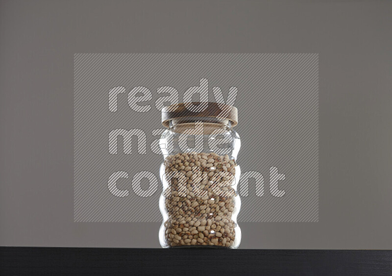 Black-eyed peas in a glass jar on black background