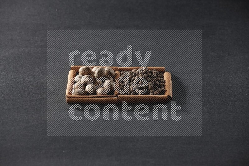 2 squares of cinnamon sticks full of nutmegs and allspice on black flooring