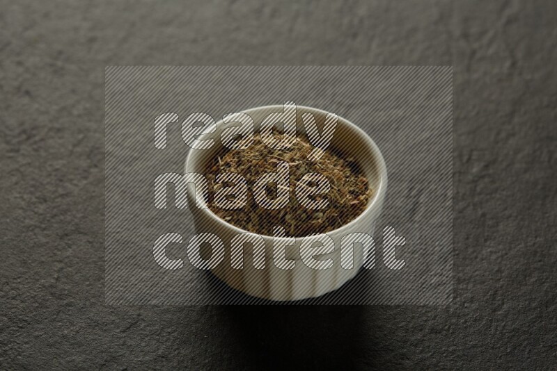 white ceramic round sauce bowl filled with herbs on grey textured countertop