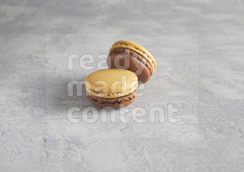 45º Shot of two Yellow and Brown Chai Latte macarons r on white  marble background